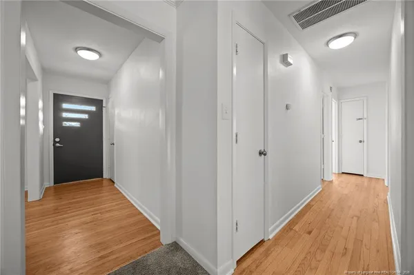 an empty room with wooden floor ceiling fan and windows