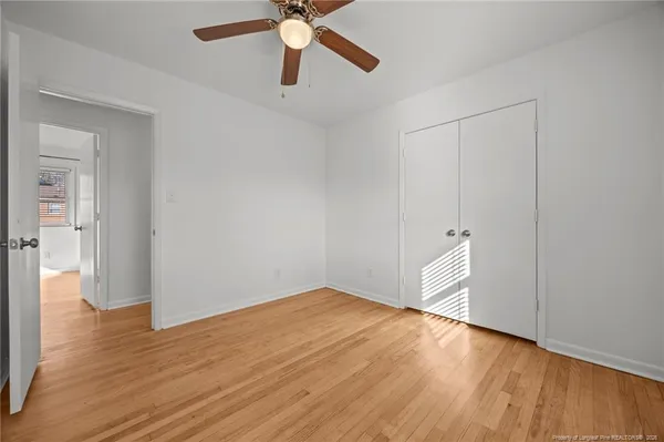 a view of empty room with wooden floor and fan