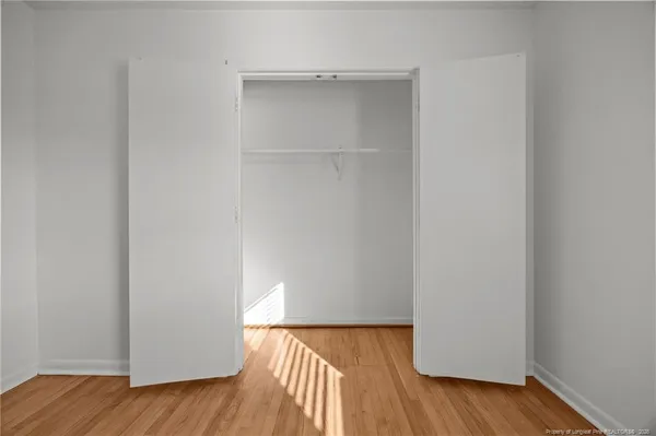 an empty room with wooden floor chandelier fan and windows