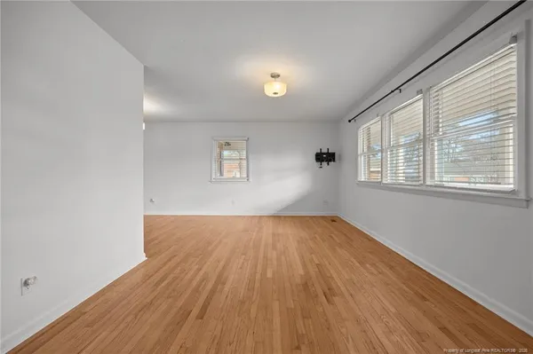 a view of an empty room with a kitchen and a window
