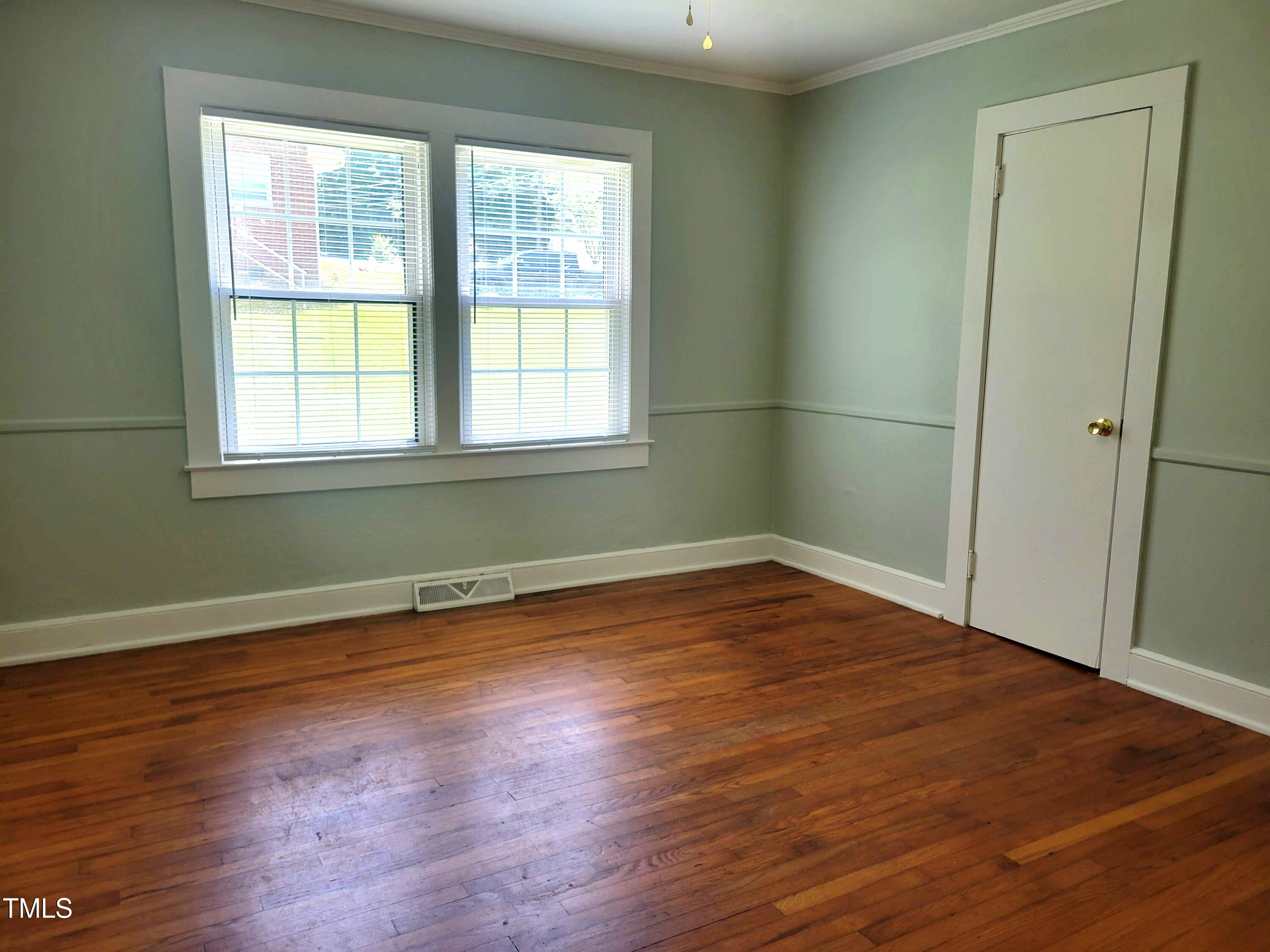 411 West Raleigh Street Siler City, NC 27344 - Photo 14 of 33 an empty room with wooden floor and windows