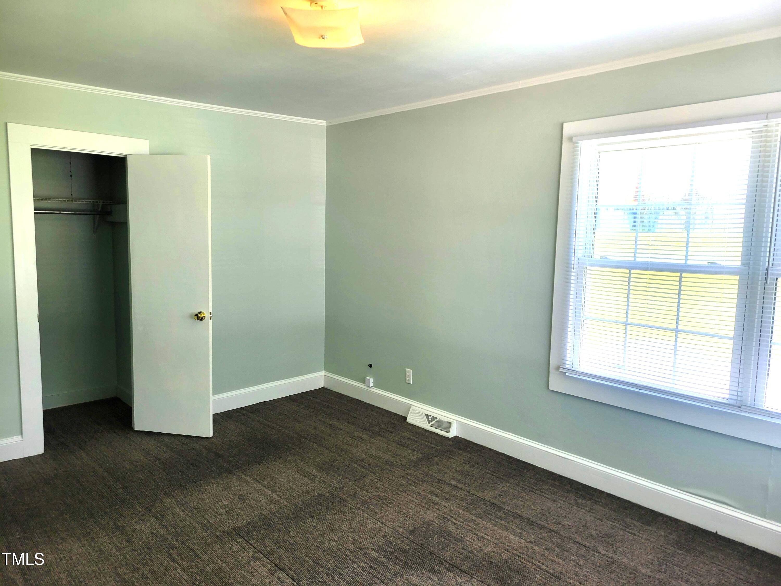 411 West Raleigh Street Siler City, NC 27344 - Photo 17 of 33 an empty room with wooden floor and windows
