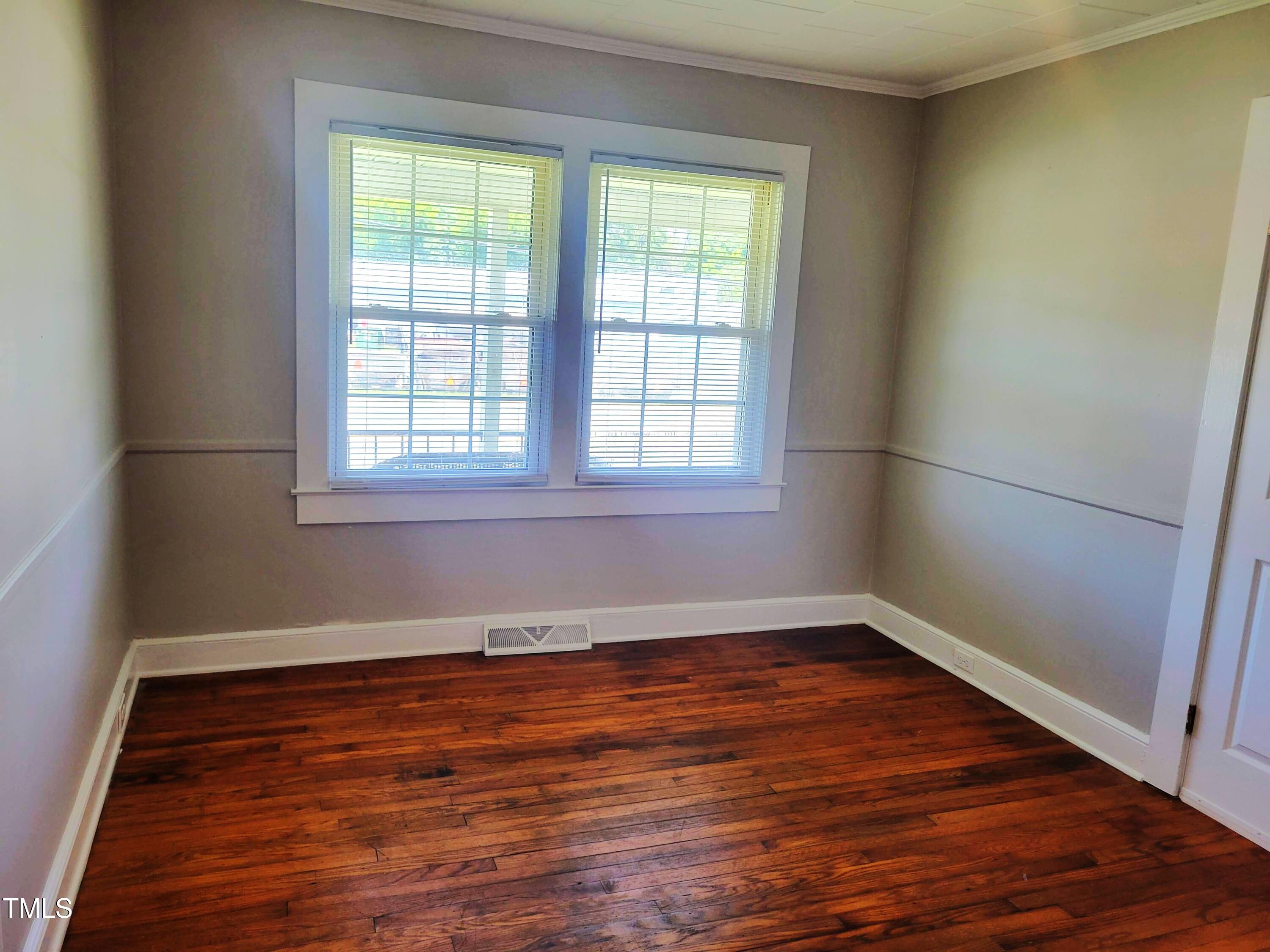 411 West Raleigh Street Siler City, NC 27344 - Photo 18 of 33 an empty room with wooden floor and windows