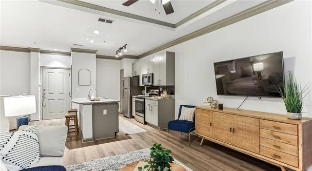 a living room with stainless steel appliances furniture and a flat screen tv