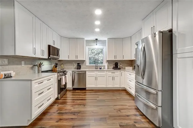 a kitchen with white cabinets stainless steel appliances and window