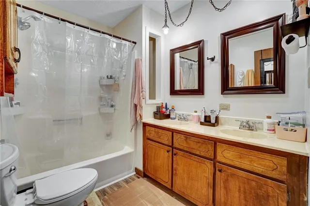 a bathroom with a granite countertop sink toilet a mirror a vanity and shower