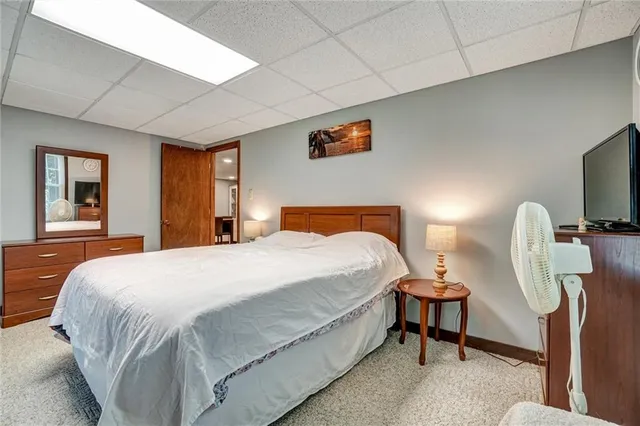 a bedroom with a bed wooden floor and lamp on dresser