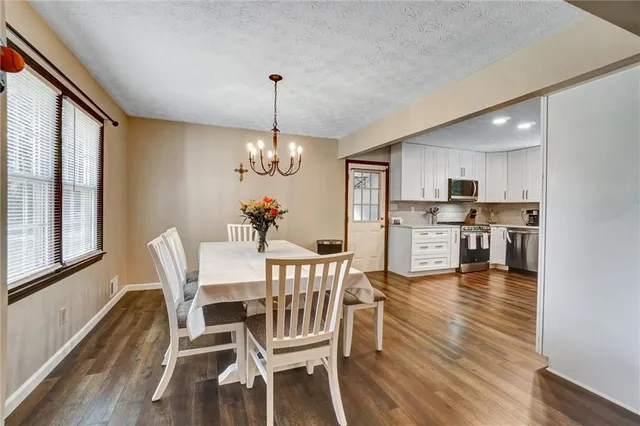 a view of a dining room and livingroom with furniture wooden floor a chandelier