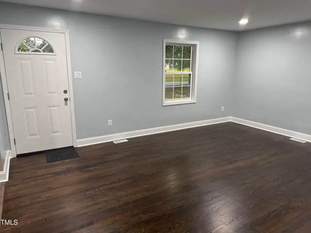 an empty room with wooden floor and window