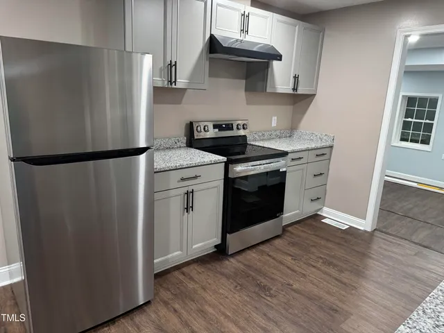 a kitchen with stainless steel appliances a refrigerator a stove and wooden floors