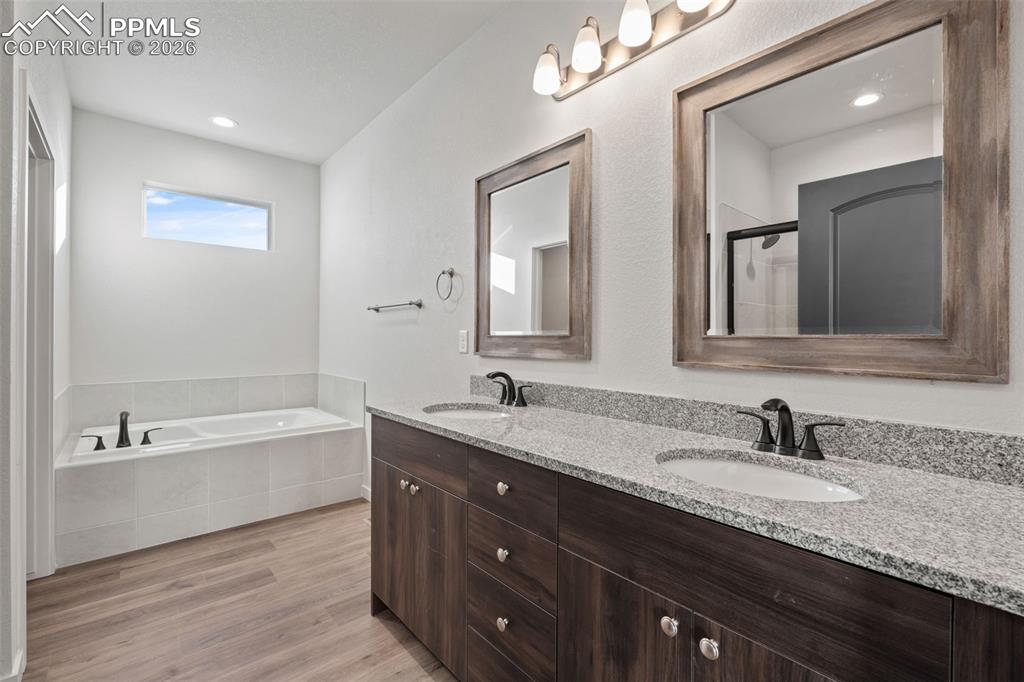 24615 Big Springs Road Calhan, CO 80808 - Photo 14 of 40 a bathroom with a granite countertop double vanity sink and mirror with bathtub