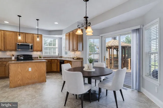 a kitchen with stainless steel appliances granite countertop a stove a sink a microwave a dining table and chairs