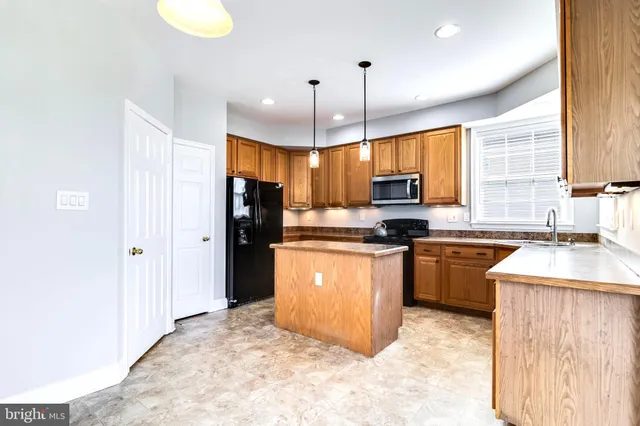 a kitchen with stainless steel appliances granite countertop a refrigerator a sink a stove and a cabinets