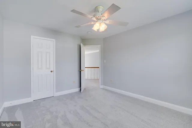 an empty room with a chandelier fan and windows