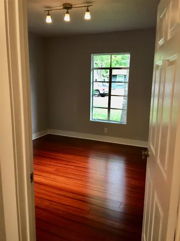 an empty room with wooden floor and windows with curtains