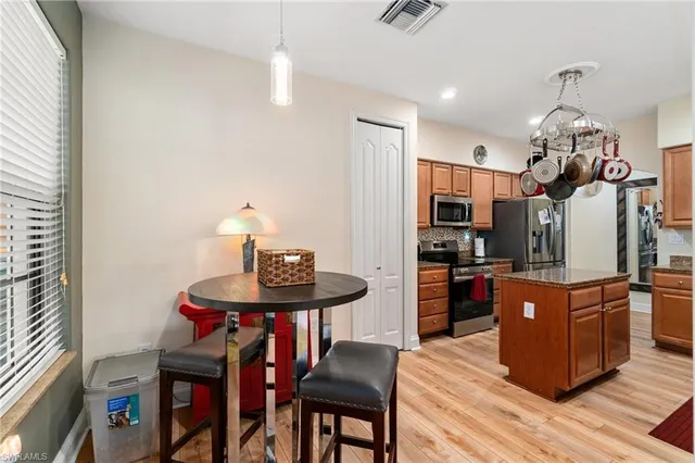 a kitchen with stainless steel appliances kitchen island granite countertop a table chairs and a refrigerator