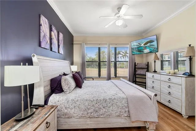 a bedroom with a large bed a chandelier and a flat tv screen on dresser