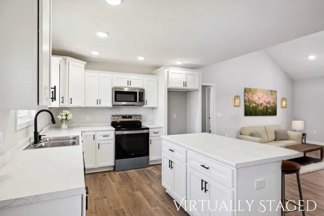 a kitchen with stainless steel appliances a sink a stove a refrigerator cabinets and a dining room