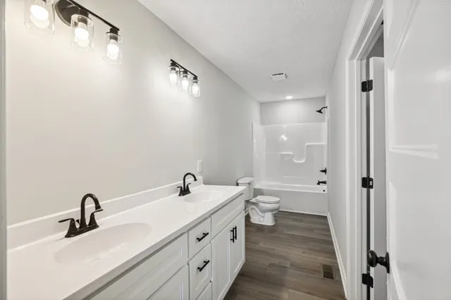 a bathroom with a double vanity sink and mirror with toilet