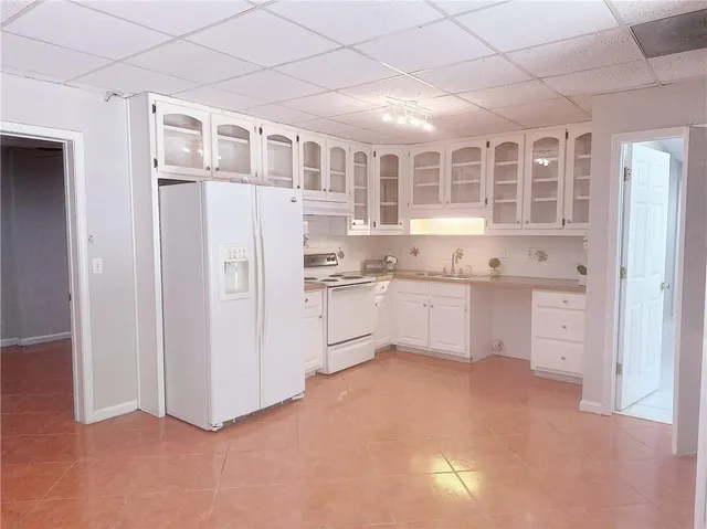 a kitchen with white cabinets and wooden floor