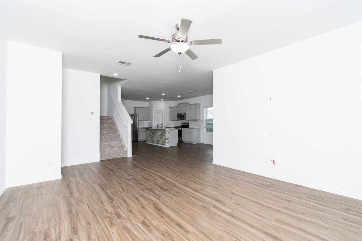 9101 Daisy Cutter Crossing Georgetown, TX 78626 - Photo 3 of 28 Unfurnished living room with ceiling fan, light wood finished floors, and stairway