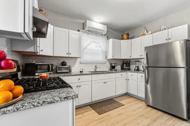 a kitchen with granite countertop kitchen island stainless steel appliances a stove refrigerator sink and cabinets
