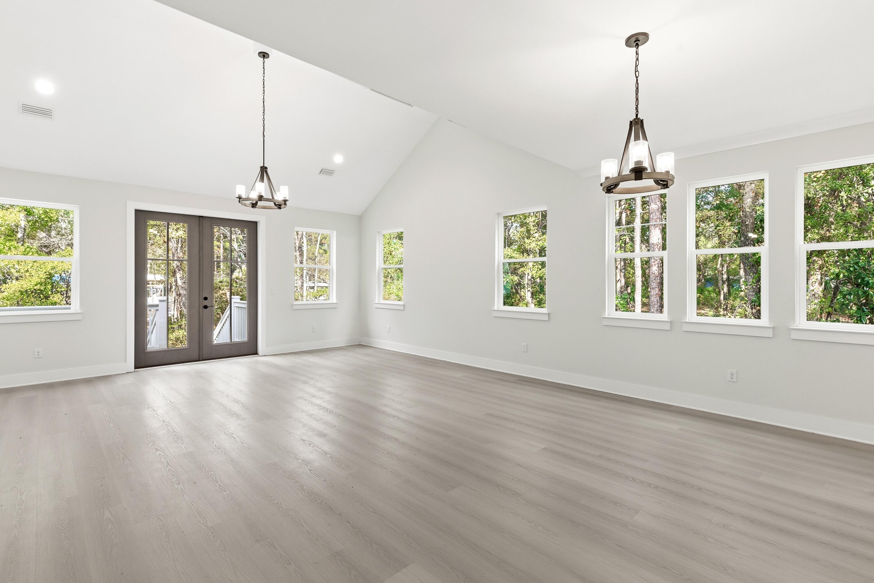 151 Redfish Pt Drive Freeport, FL 32439 - Photo 15 of 40 an empty room with wooden floor chandelier and windows