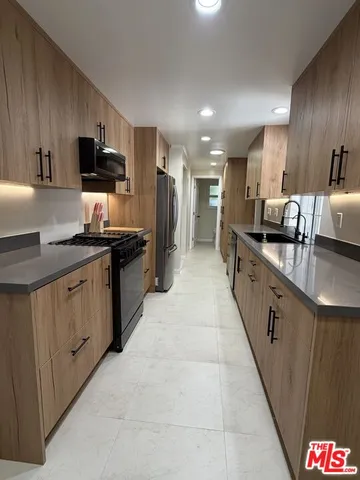 a kitchen with stainless steel appliances a sink stove and refrigerator