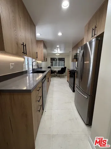 a kitchen with stainless steel appliances granite countertop a refrigerator a sink a stove and oven