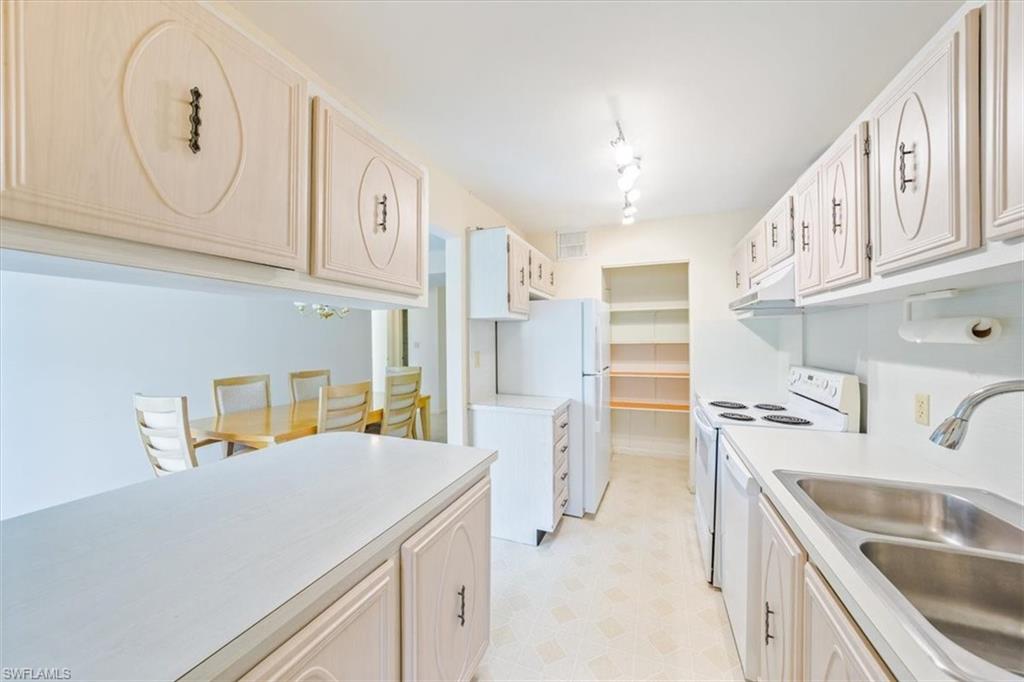 788 Park Shore Drive, Unit E20 Naples, FL 34103 - Photo 14 of 37 a kitchen that has a lot of cabinets in it and wooden floors