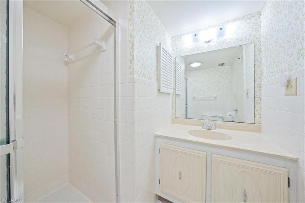 788 Park Shore Drive, Unit E20 Naples, FL 34103 - Photo 23 of 37 a bathroom with a sink vanity and a mirror