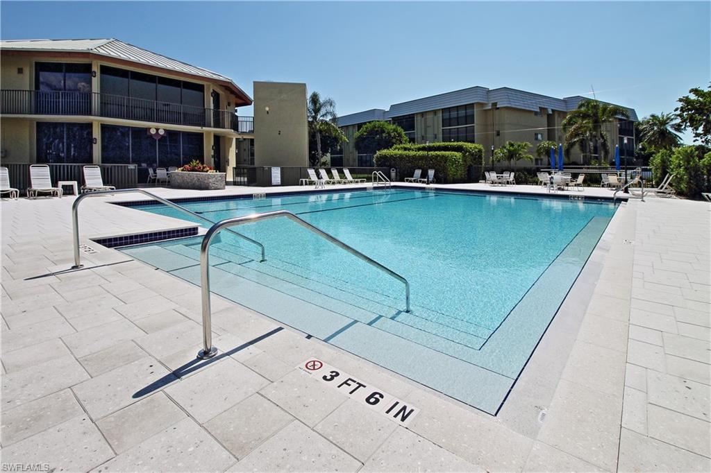 788 Park Shore Drive, Unit E20 Naples, FL 34103 - Photo 36 of 37 a patio with a table and chairs under an umbrella