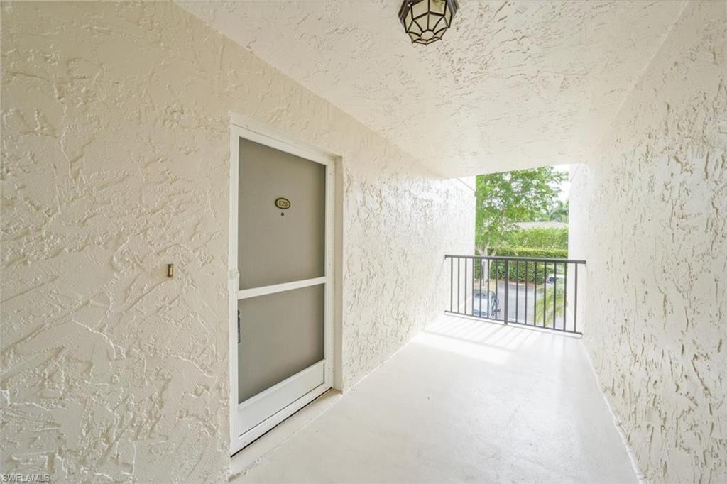788 Park Shore Drive, Unit E20 Naples, FL 34103 - Photo 4 of 37 a view of a hallway to an empty room with wooden floor and a window