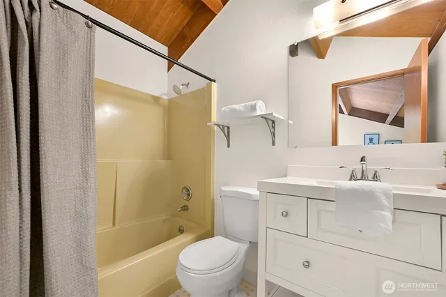 a bathroom with a bathtub shower sink vanity mirror and toilet