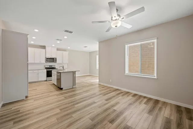 a view of kitchen with kitchen island stainless steel appliances sink cabinets and wooden floor