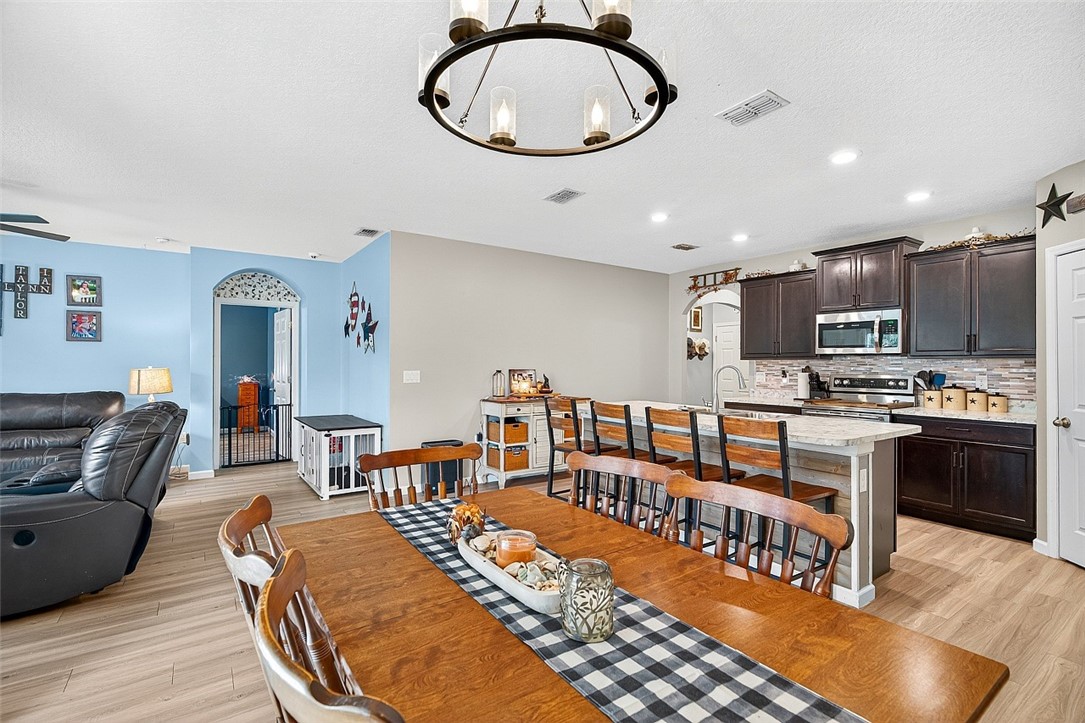 233 Periwinkle Drive Sebastian, FL 32958 - Photo 9 of 34 a living room with stainless steel appliances kitchen island granite countertop a stove a kitchen island a dining table and chairs with wooden floor