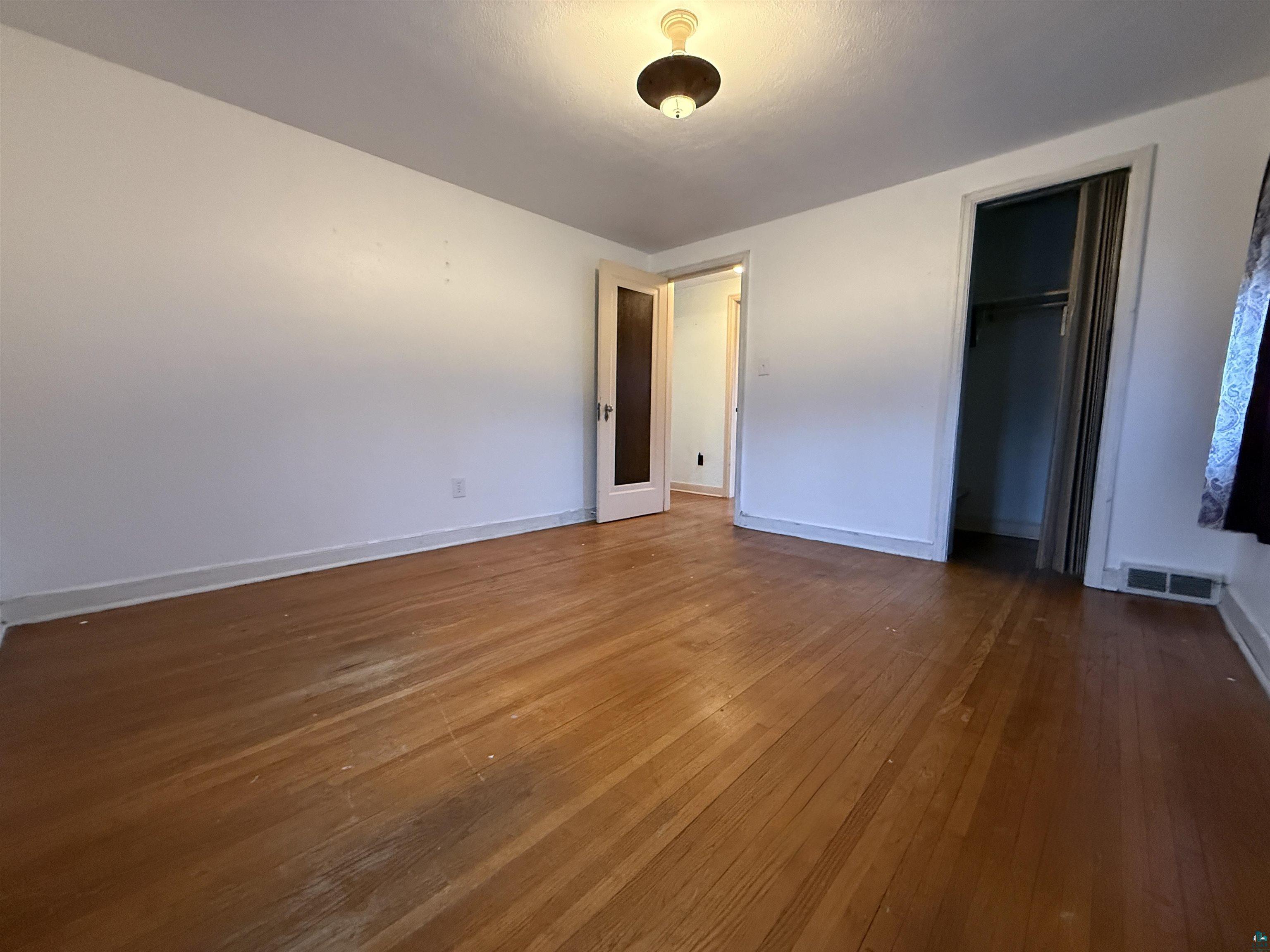 3001 3rd Avenue West Hibbing, MN 55746 - Photo 27 of 38 Unfurnished bedroom with dark wood finished floors and a closet