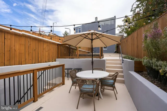 a view of backyard with seating space and wooden fence