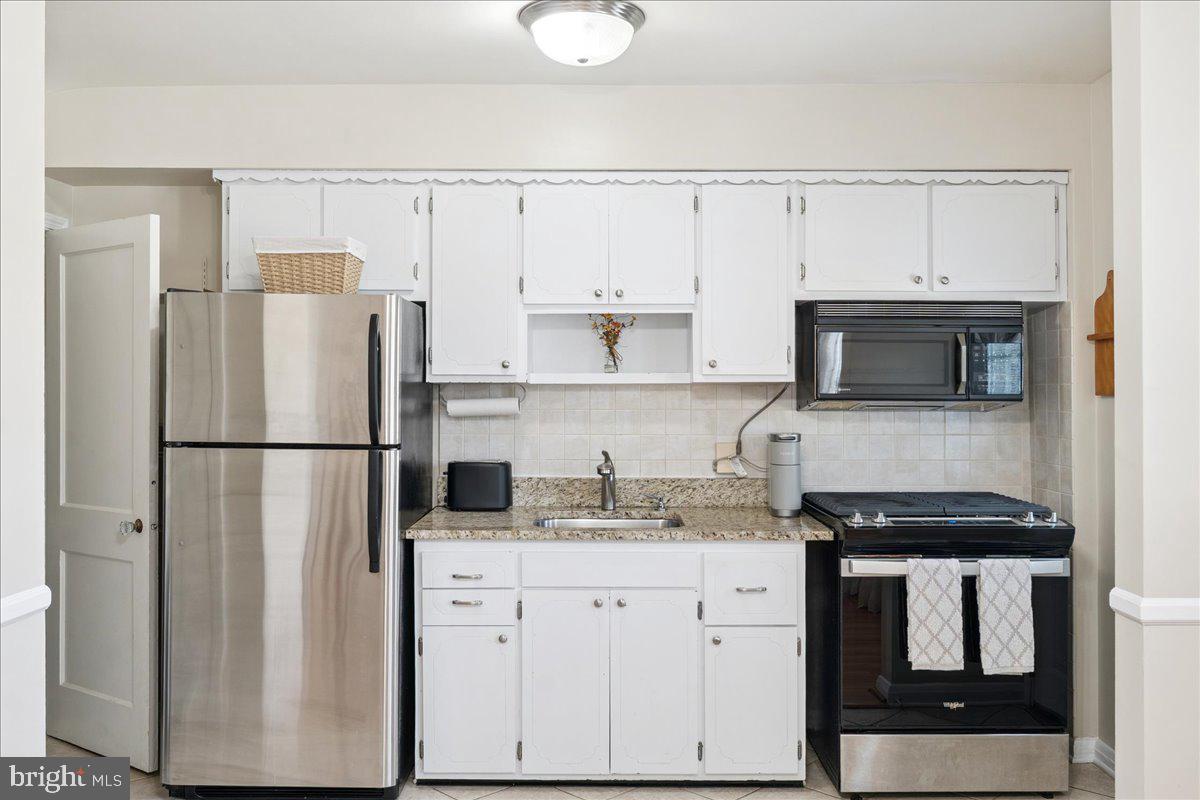 7024 Conley Street Baltimore, MD 21224 - Photo 8 of 20 a kitchen with a refrigerator a stove and white cabinets