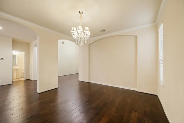 a view of a hallway with wooden floor and a chandelier