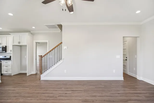 a large kitchen with stainless steel appliances granite countertop a stove a sink a refrigerator and white cabinets with wooden floor