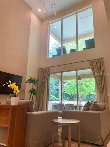 a living room with furniture kitchen view and a chandelier