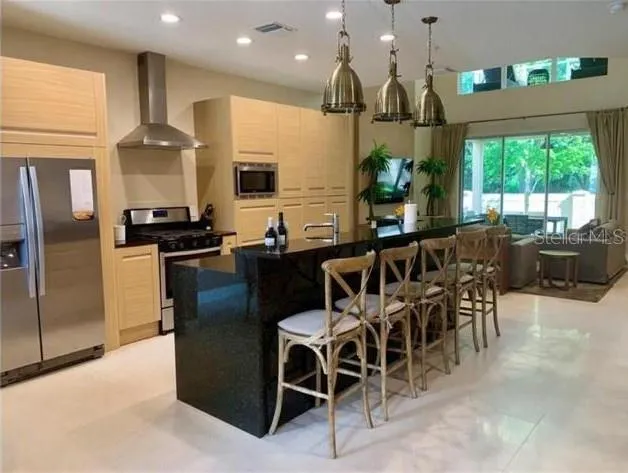 a kitchen with stainless steel appliances kitchen island granite countertop a stove a refrigerator a sink a dining table and chairs with wooden floor