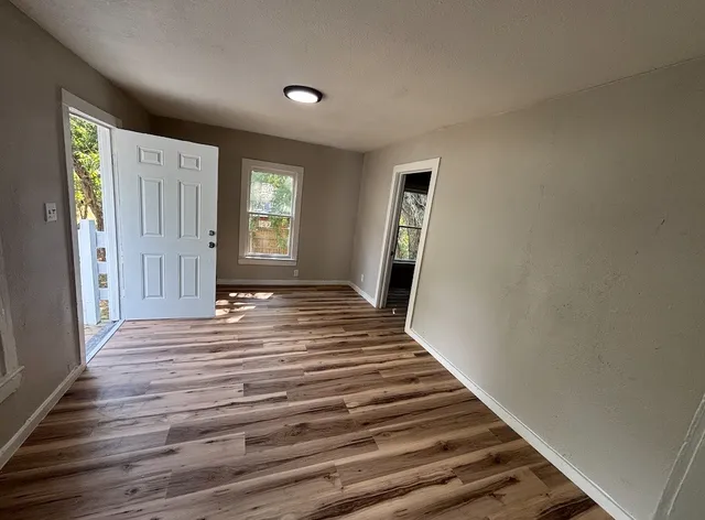a view of empty room with window and wooden floor