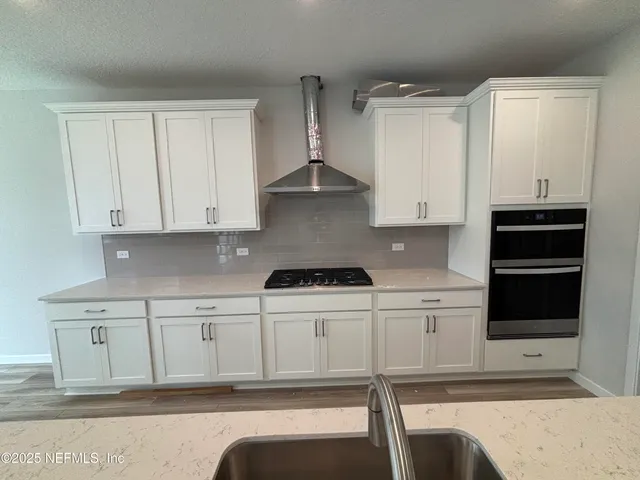 a large kitchen with stainless steel appliances kitchen island a large counter top and wooden floors