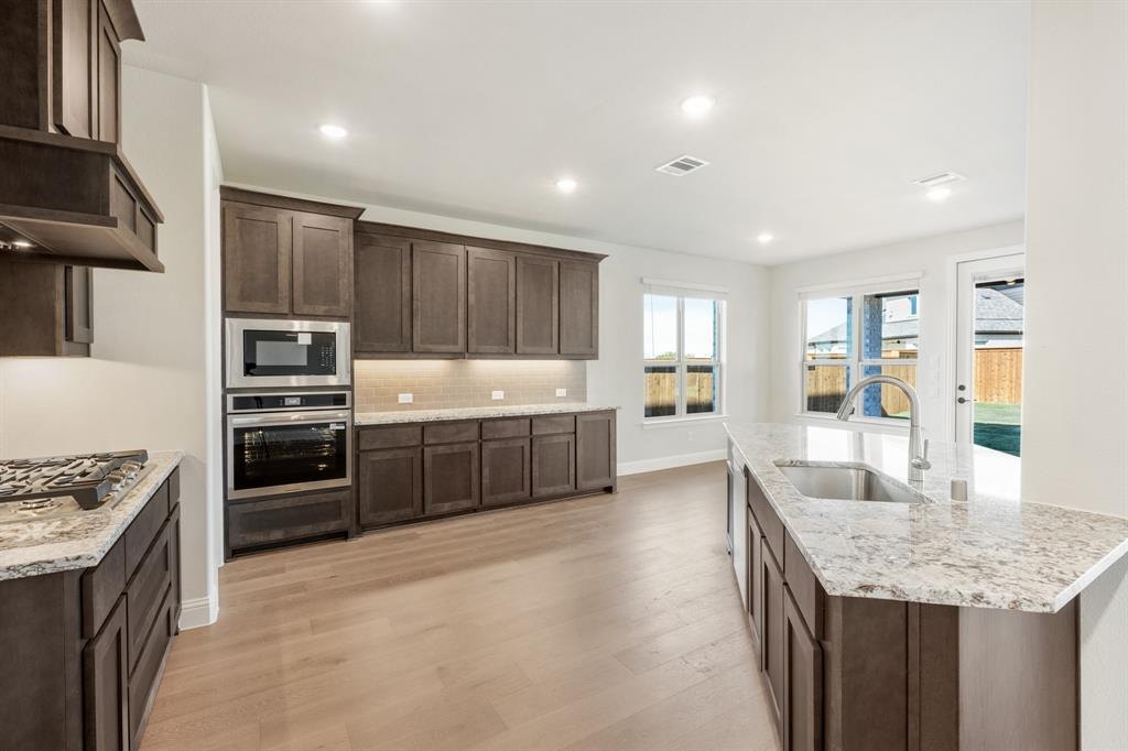 14422 McClint Street Pilot Point, TX 76258 - Photo 9 of 40 a kitchen with kitchen island granite countertop a stove sink and refrigerator