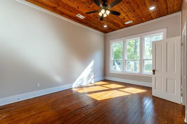 a view of empty room with wooden floor and fan