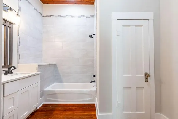 a bathroom with a tub shower vanity and a sink