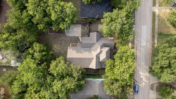 an aerial view of a house with outdoor space and trees all around