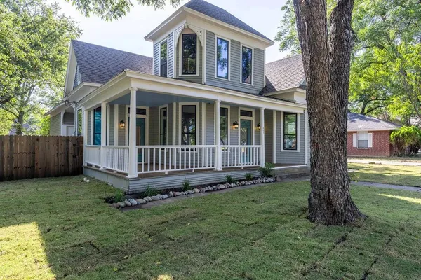 a view of a house with a yard and a large tree